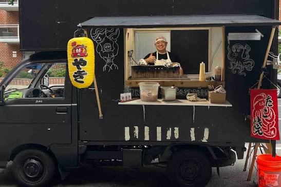 Black Kei truck food cart decorated with chalk art, vendor serving at the window