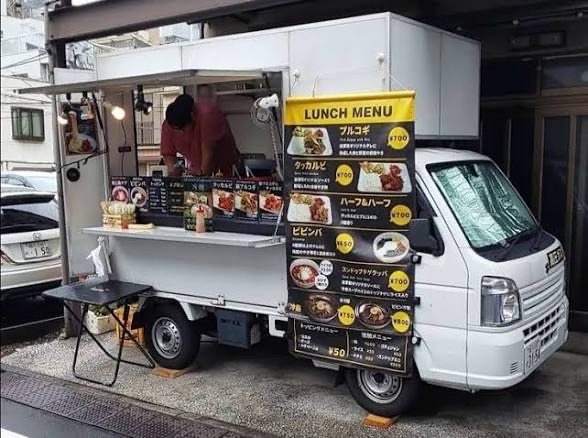 White Kei truck with a printed lunch menu board pinned to the box